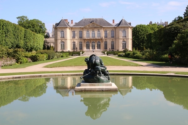 a sculpture in a pond in front of a grand building