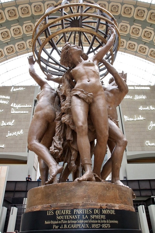a statue of 4 women holding up a globe