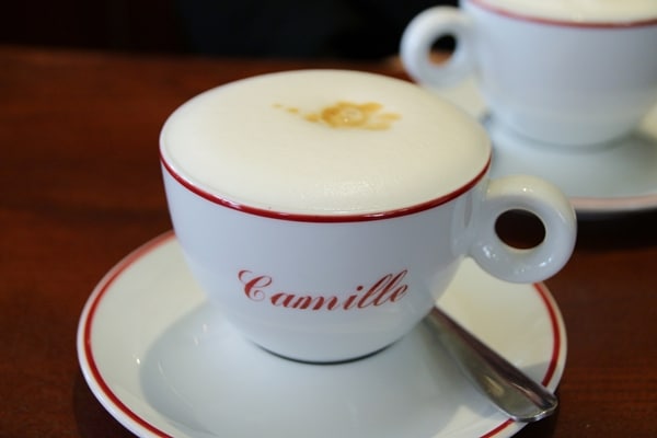 cappuccino in a white and red cup that says Camille