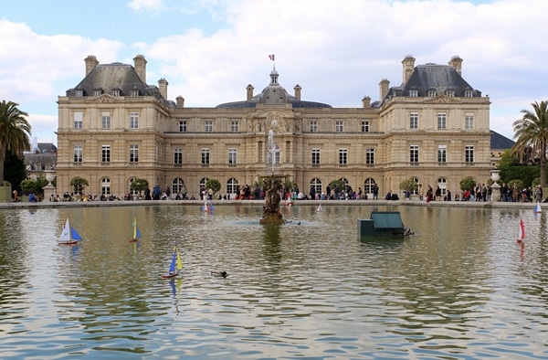 A group of people around a fountain in front of Luxembourg Palace