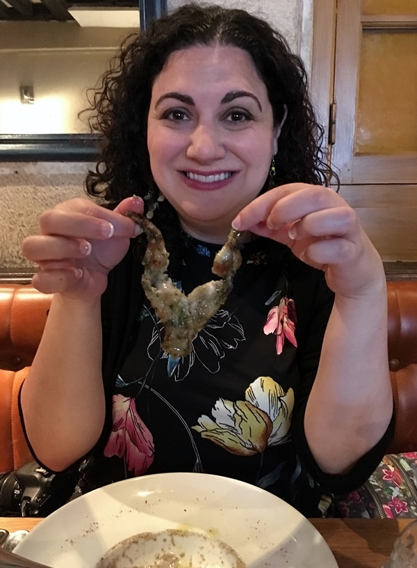 A woman holding up frogs legs between her fingers
