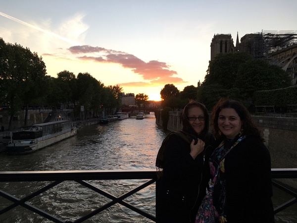 2 women on a river bridge at sunset