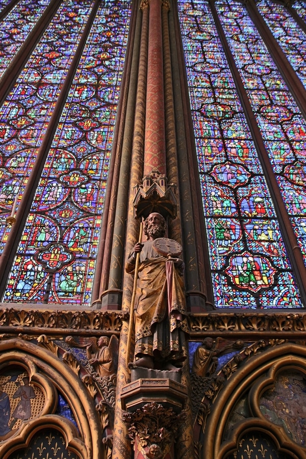 statue of an apostle beneath tall stained glass windows