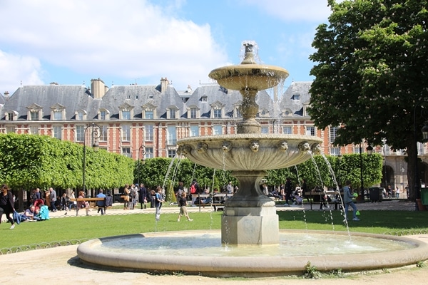 A fountain in a large grassy Parisian square