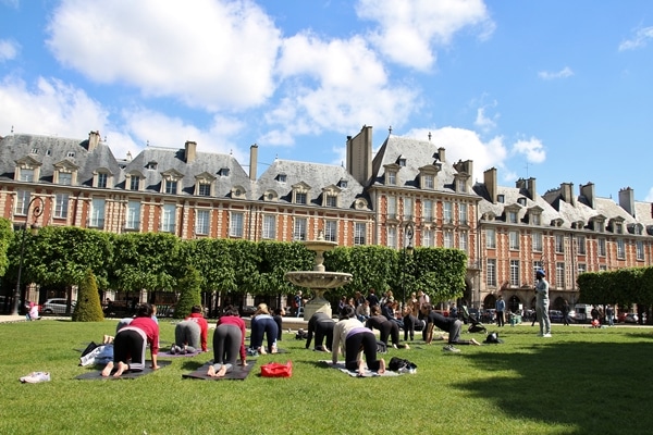 A group of people doing yoga in the grass at Place des Vosges in Paris