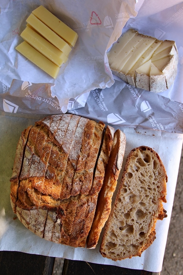 sliced bread and a variety of sliced cheeses on a park bench