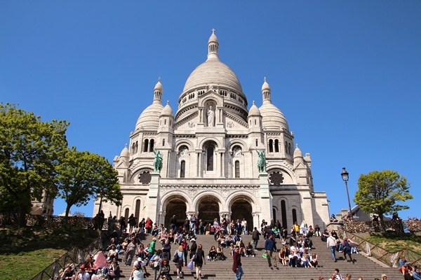 A group of people standing in front of Sacré-Cœur Basilica in Paris