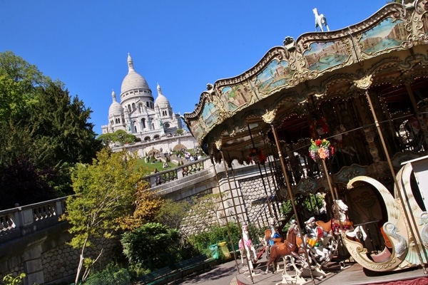 a carousel at the bottom of a hill with Sacre Coeur Basilica at the top