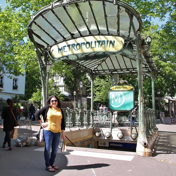 a woman standing in front of an ornate Parisian metro sign