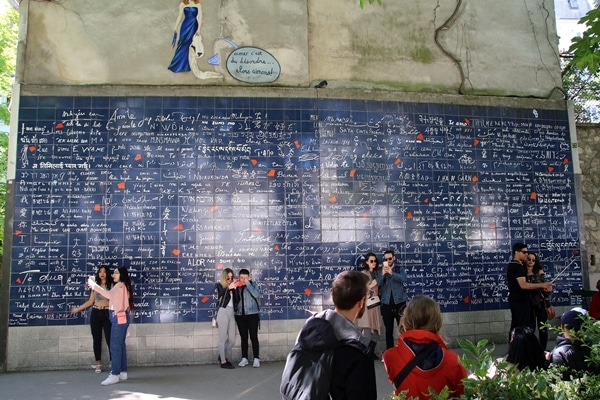 groups of people standing in front of a blue wall with writing