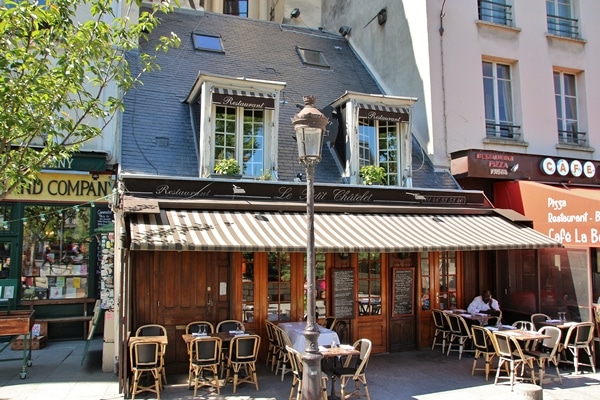 exterior of a quaint restaurant with striped awning and tables outside