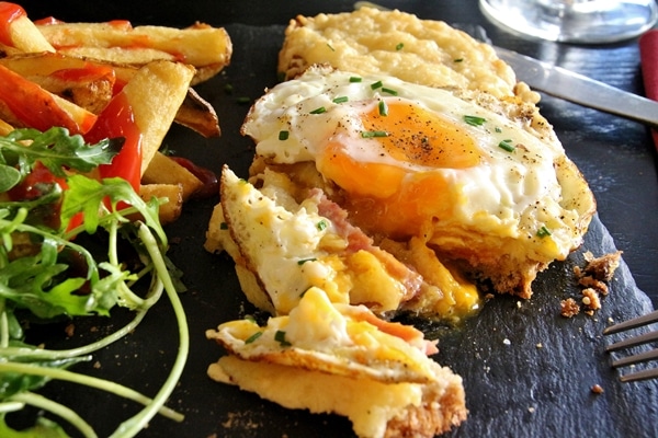 A close up of a croque madame sandwich with a few pieces cut off