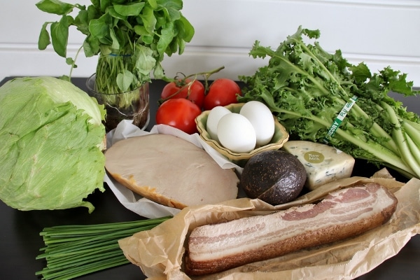 The ingredients for Brown Derby Cobb Salad: iceberg lettuce, watercress, tomatoes, turkey, eggs, chicory, avocado, blue cheese, bacon, and chives