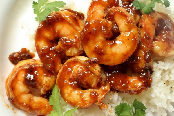 Pomegranate sriracha shrimp served over white rice with cilantro garnish