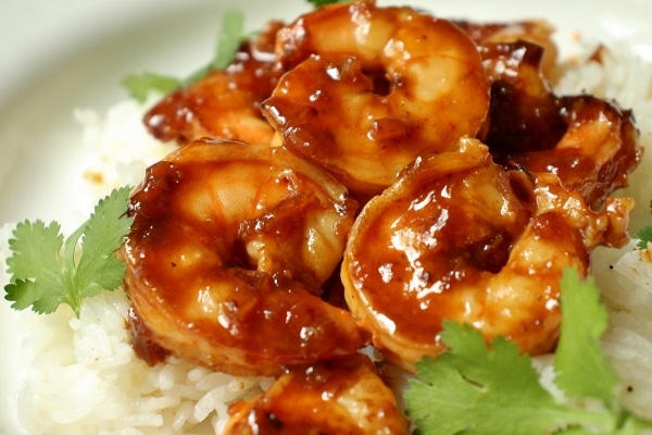 closeup of pomegranate sriracha shrimp served over white rice with cilantro garnish