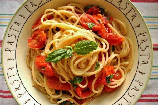overhead view of spaghetti with tomato and basil in a shallow bowl