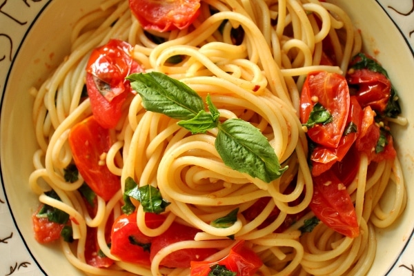 overhead view of spaghetti with a cherry tomato and basil sauce