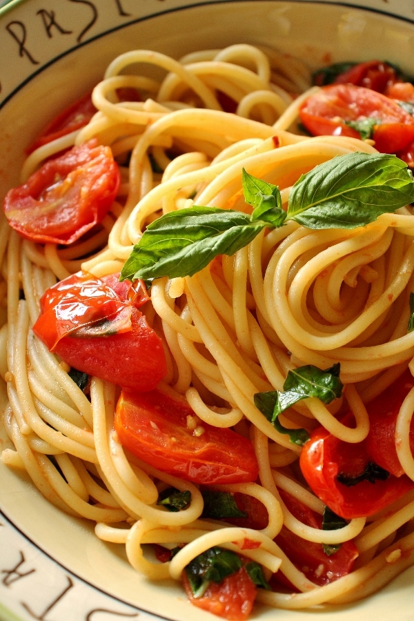 closeup of spaghetti with a cherry tomato and basil sauce
