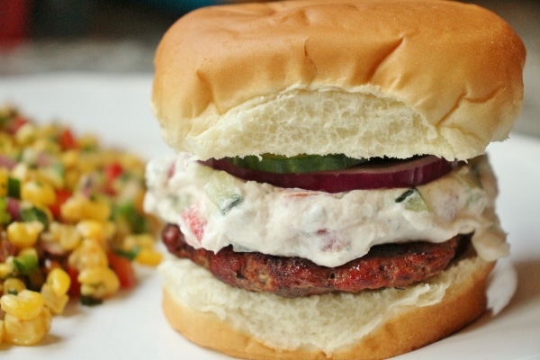 side view of a burger with goat cheese, red onion, and sliced cucumber