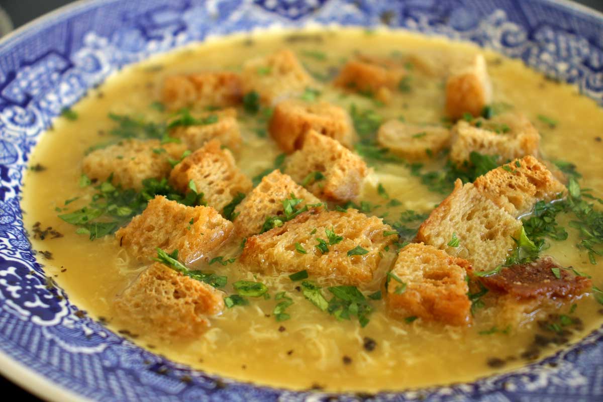 Closeup of a bowl of Czech garlic soup topped with rye croutons.