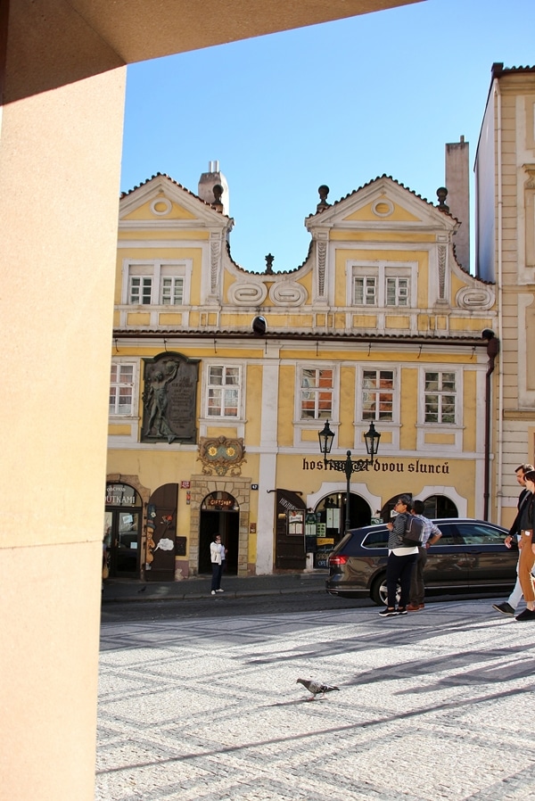 People walking down the street in front of an ornate yellow building