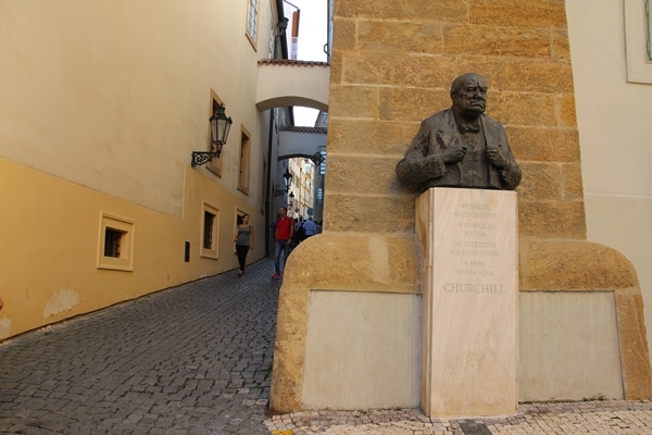 a statue of Winston Churchill at the base of a narrow cobblestone street