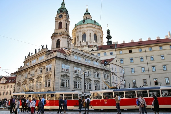 A red tram in front of a large church with a green dome