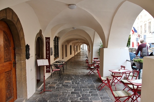 a covered walkway with tables and chairs on one side