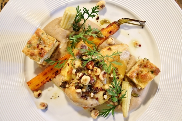 a plate of chicken with hazelnuts, carrots and bread cubes