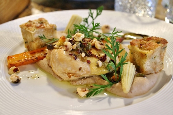 side view of a plate of chicken with hazelnuts and baby corn