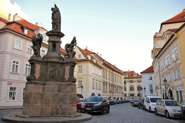 a small city square with a statue and cars