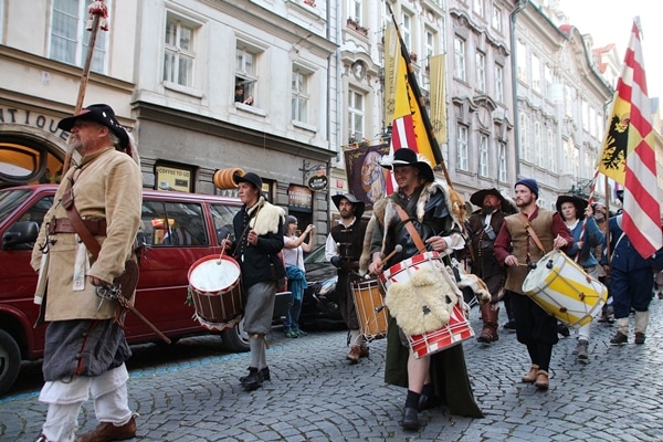 A group of people marching down the street with drums and flags