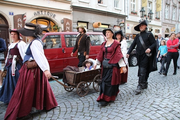 A group of people walking down a street with a child in a wagon