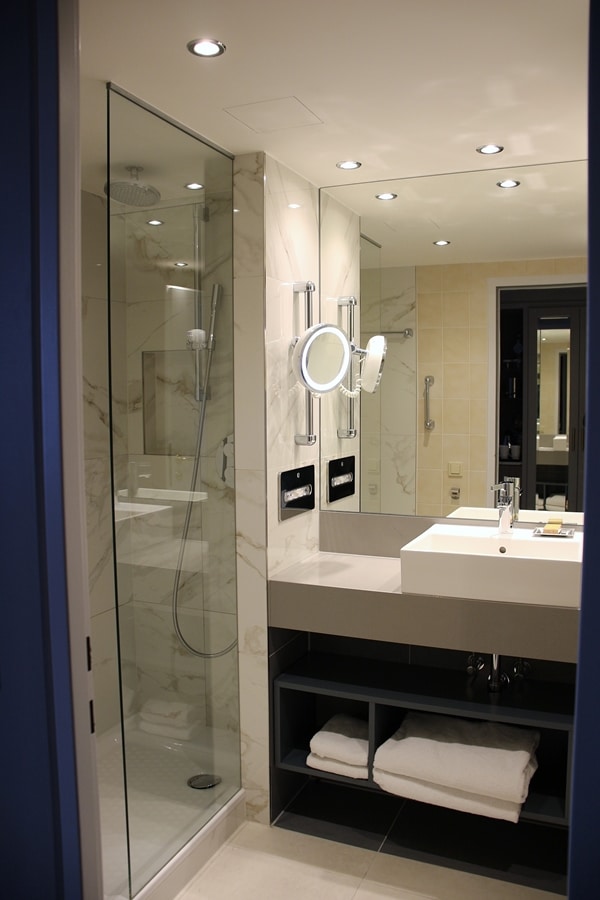 A shower, sink and large mirror in a hotel room bathroom