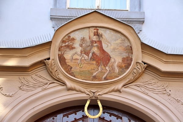 an illustration of a man on a horse with a gold horseshoe hanging below it
