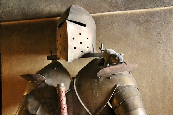 a suit of armor with a fake rat sitting on the shoulder