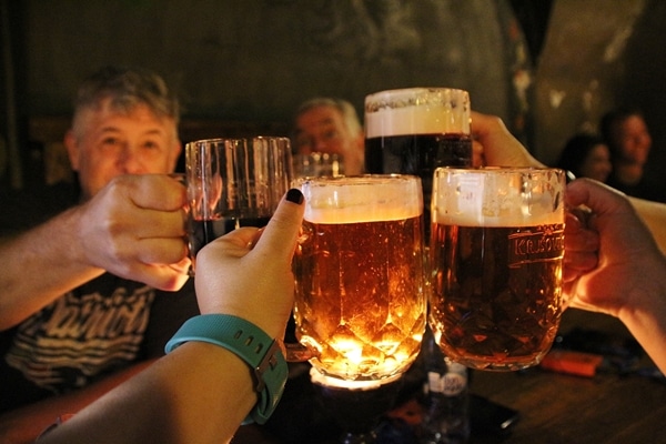 4 glasses of beer clicking each other over a table