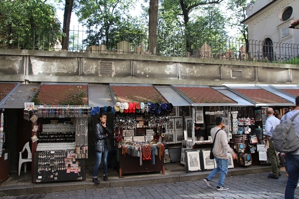 small shops on a street beneath a cemetery