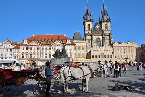 A person riding a horse drawn carriage in front of a building