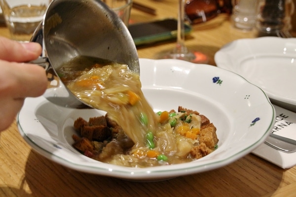 pouring soup from a small saucepan into a wide bowl