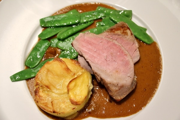 roasted meat with potato gratin and snow peas over brown sauce