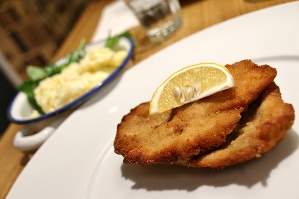 a plate of schnitzel with potato salad in the background