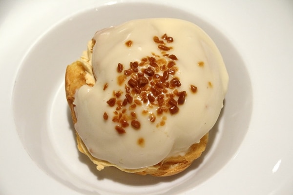 overhead view of a caramel profiterole on a white dish