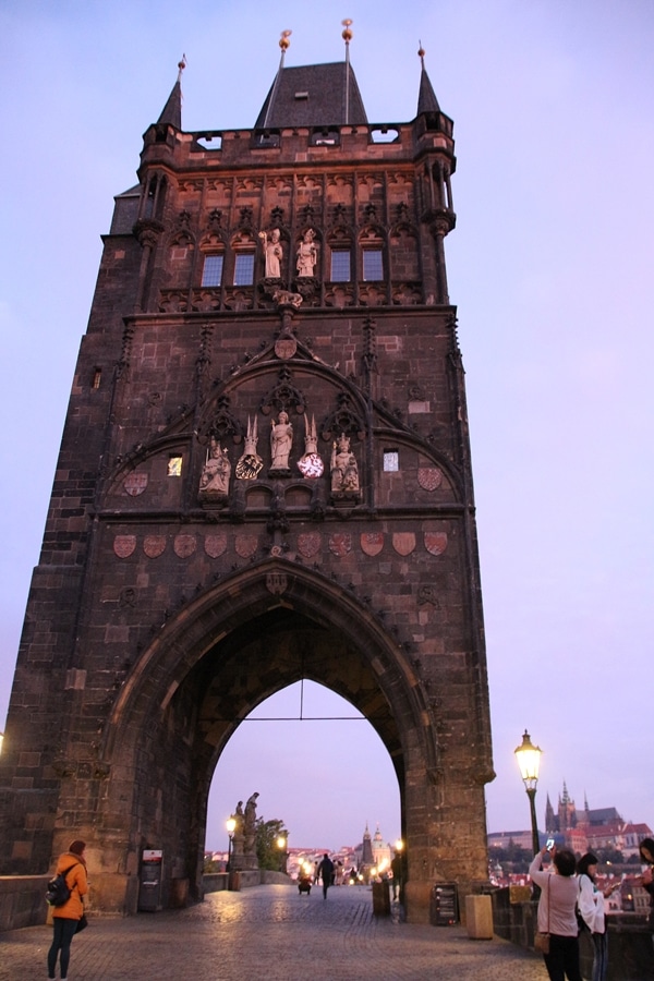 A large stone tower at the end of a bridge at dawn