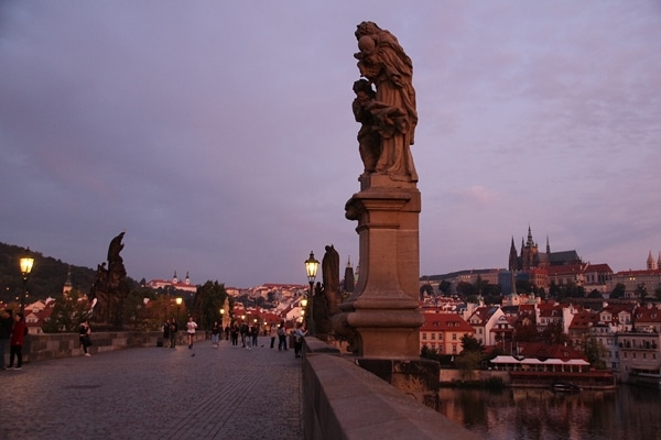 statues on nearly empty Charles Bridge at dawn