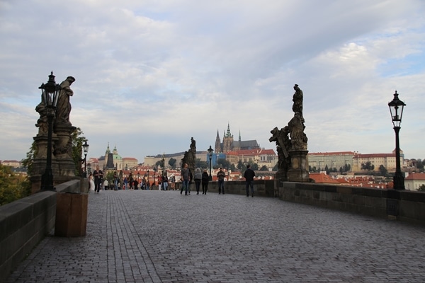 view of statues and Prague Castle from nearly empty Charles Bridge