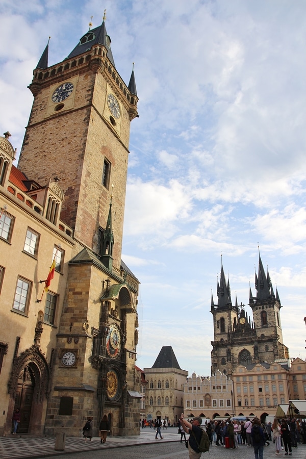 morning in a Prague square with a large clock tower and church