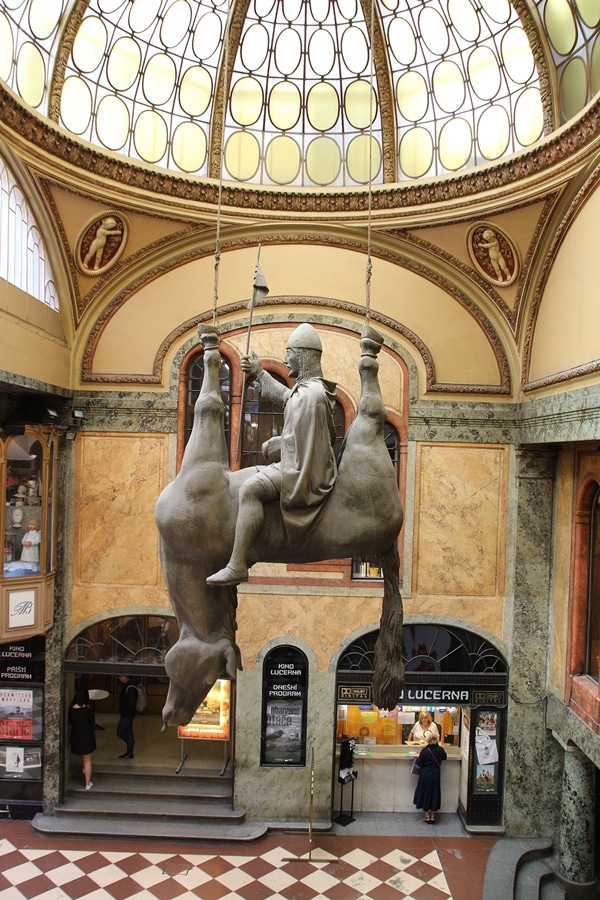 a statue of a man on an upside horse hanging from the ceiling