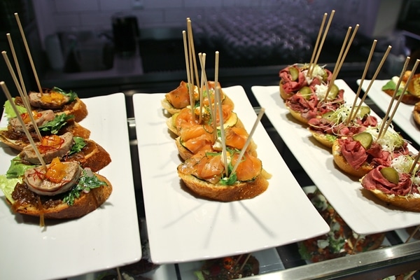 open-faced sandwiches on white plates with skewers sticking out of the tops