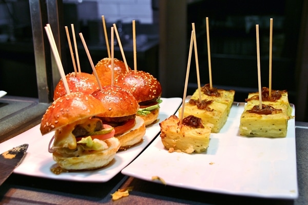 small burgers and other foods skewered with wooden sticks